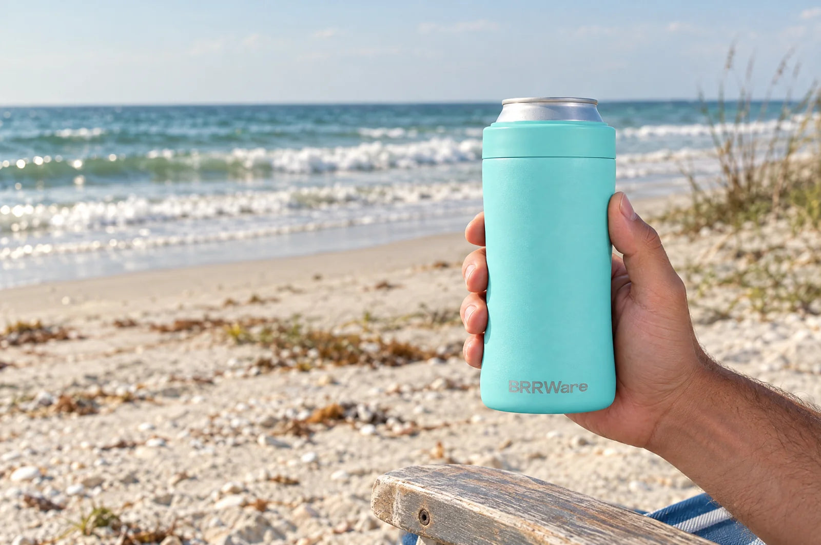 An Aqua BRRHolder held beside the ocean.